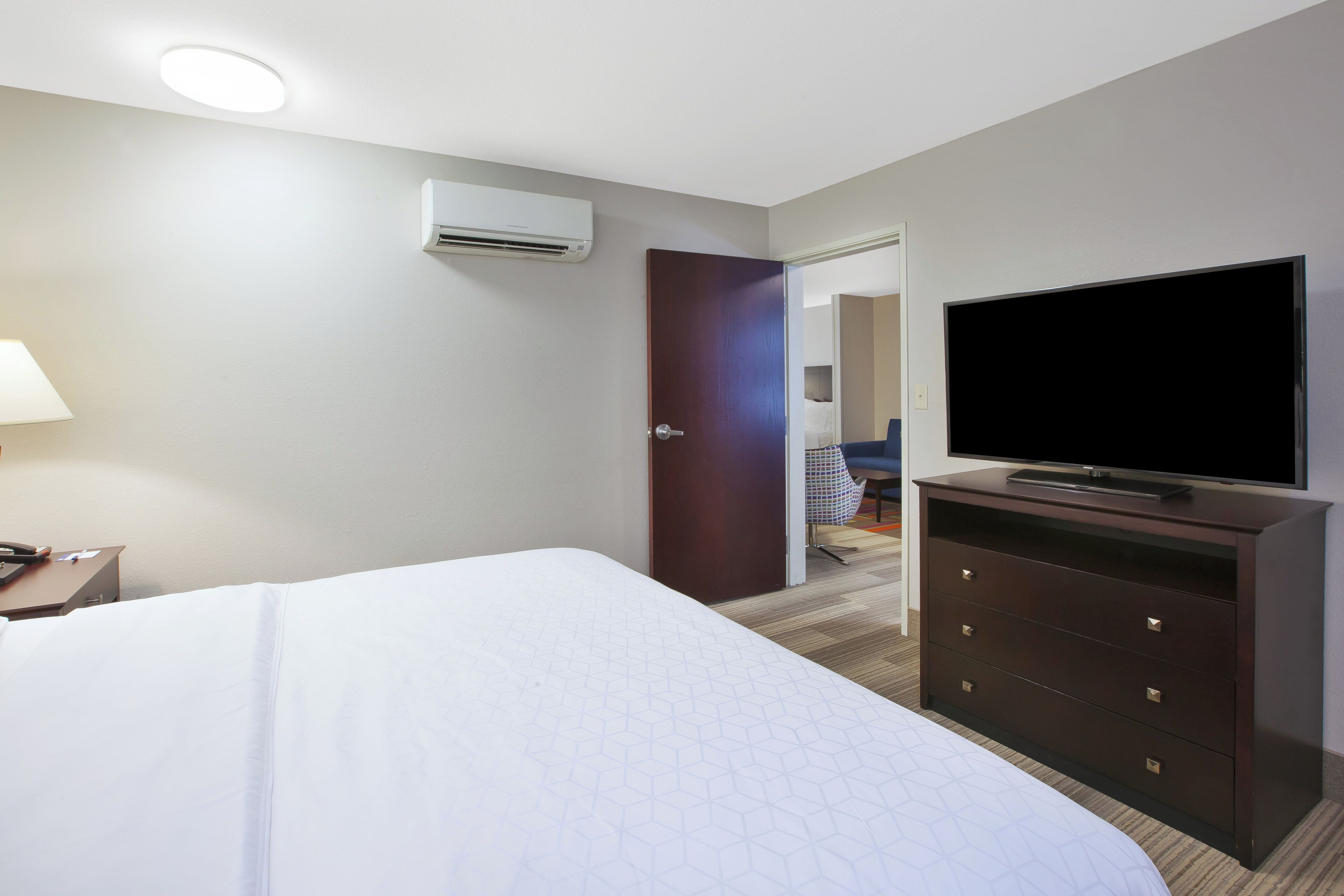 Een hotelkamer met een bed, een dressoir, een televisie en een airconditioner.