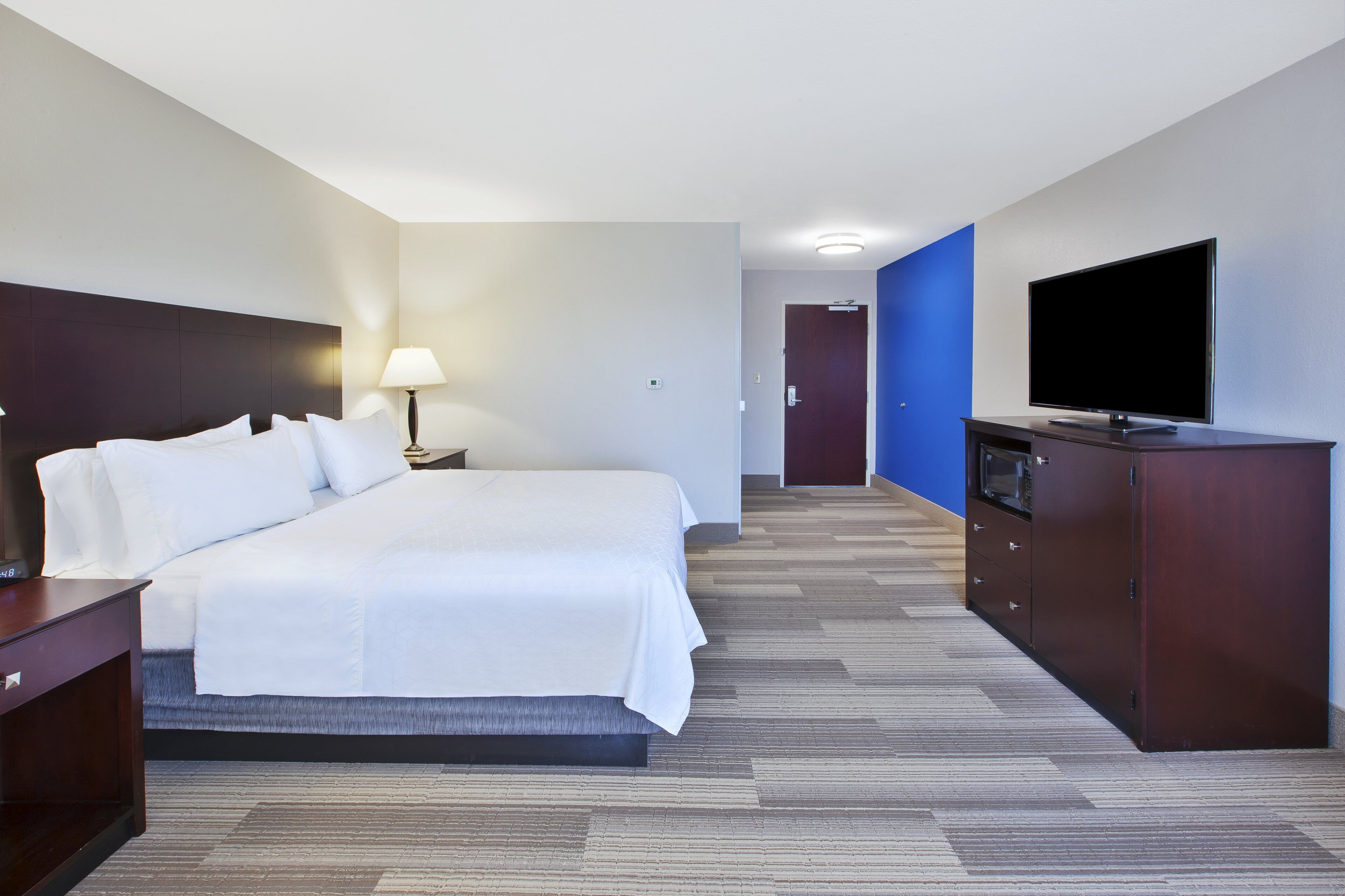 Una habitación de hotel con cama, televisión, escritorio y lámpara.