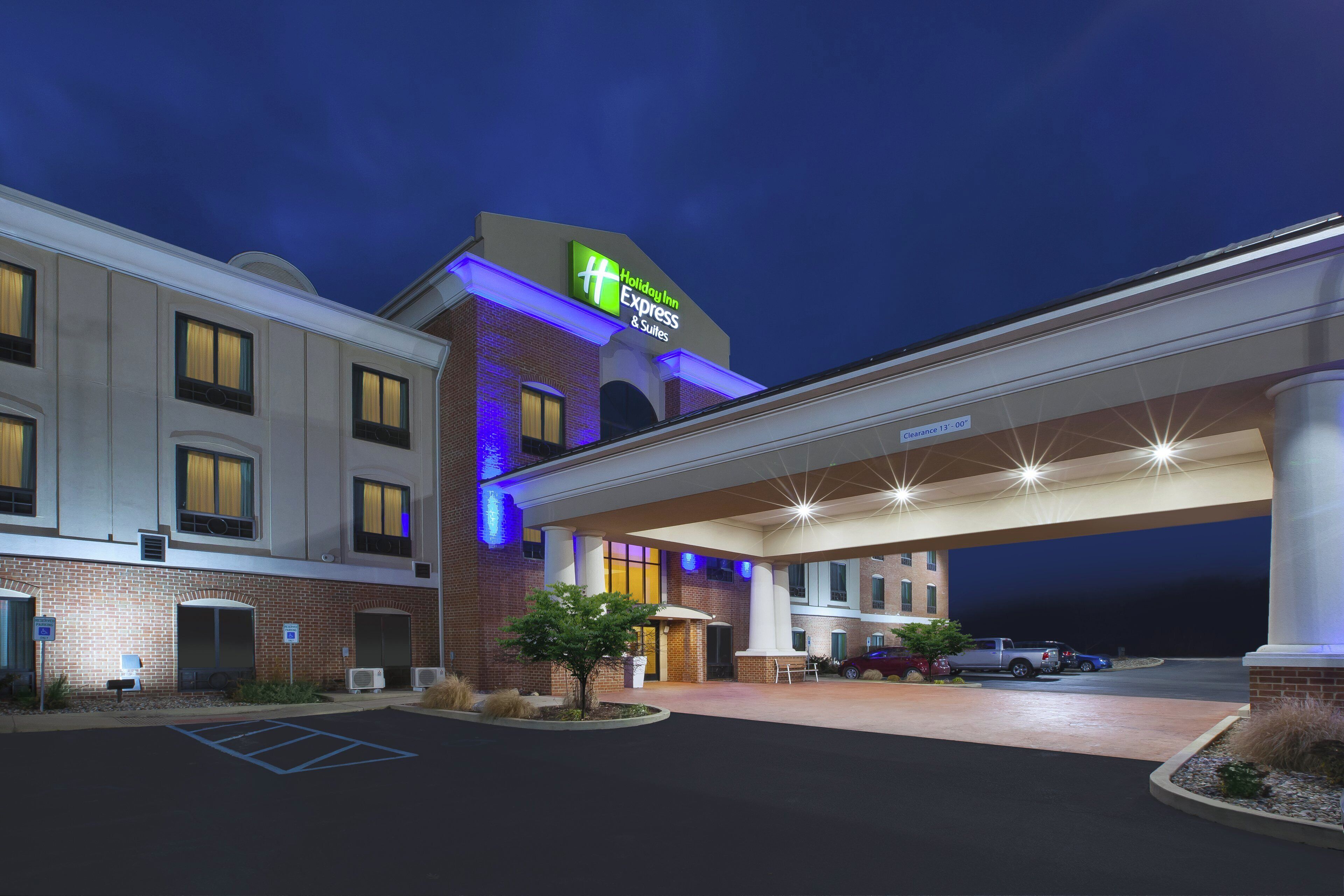 Un hotel Holiday Inn Express & Suites con fachada de ladrillo, amplias ventanas y zona de estacionamiento cubierta.