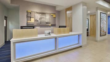 A reception desk with a modern design, a wall-mounted sign, and a blue-lit panel.