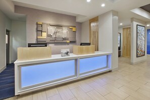A reception desk with a modern design, a wall-mounted sign, and a blue-lit panel.