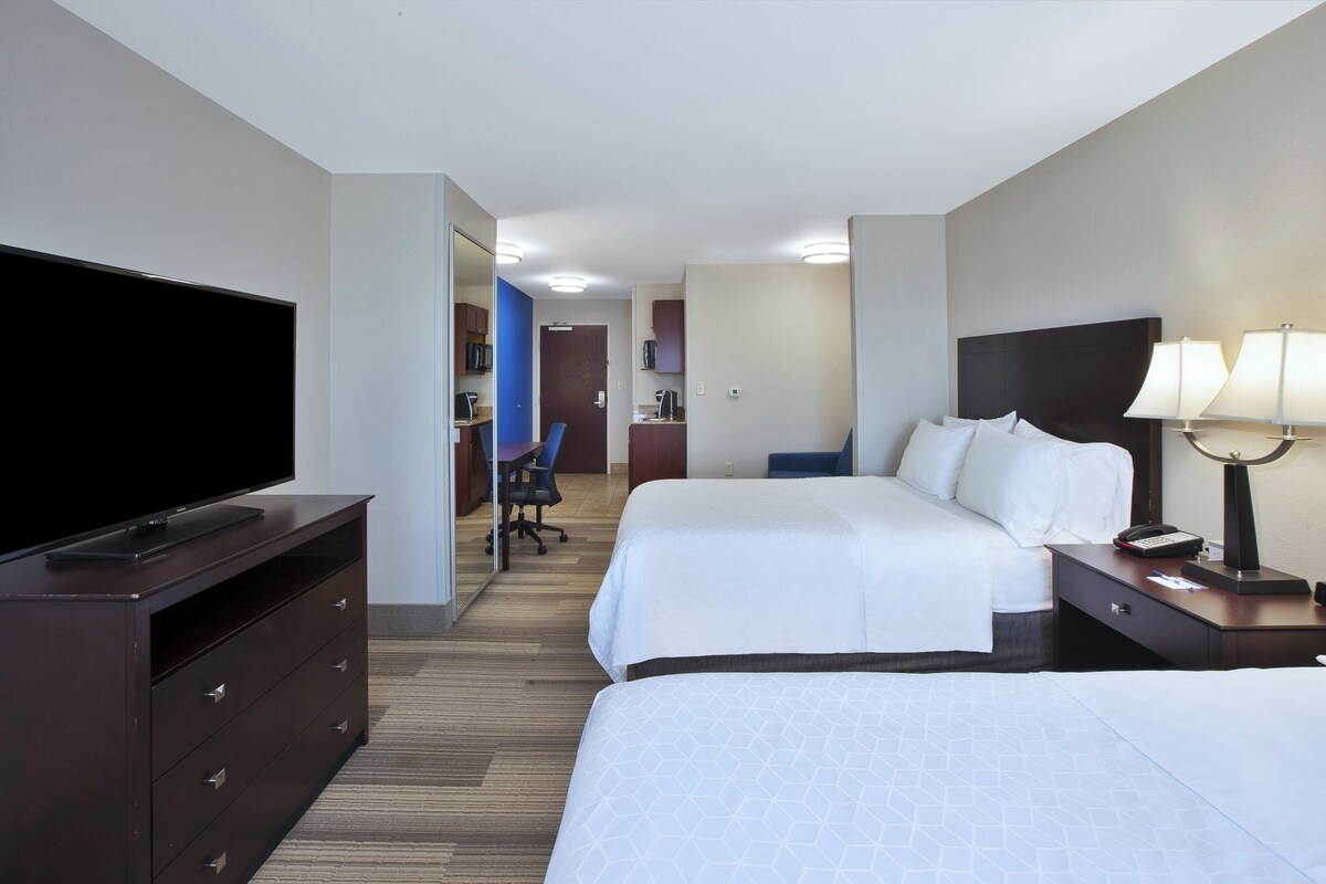 Een hotelkamer met een televisie, twee bedden, een bureau en een lamp.