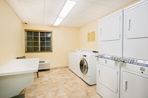Una sala de lavandería con lavadora, secadora y una mesa con sillas.