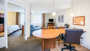 Een hotelkamer met een bed, een bureau, een stoel, een televisie en een eettafel.