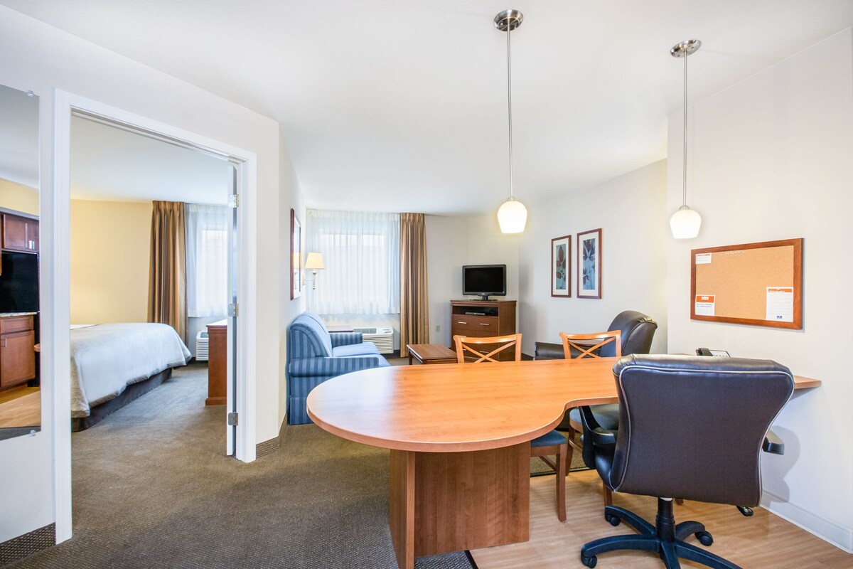 Een hotelkamer met een bed, een bureau, een stoel, een televisie en een eettafel.