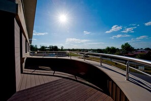A wooden deck with a metal railing, a clear sky, and a sun shining.
