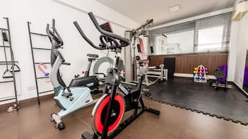 A gym with exercise equipment, a weight bench, and a yoga mat area.
