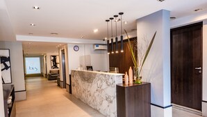 A modern reception area with a marble counter, a clock, and a reception desk. - Hotel Bys Palermo (Buenos Aires)