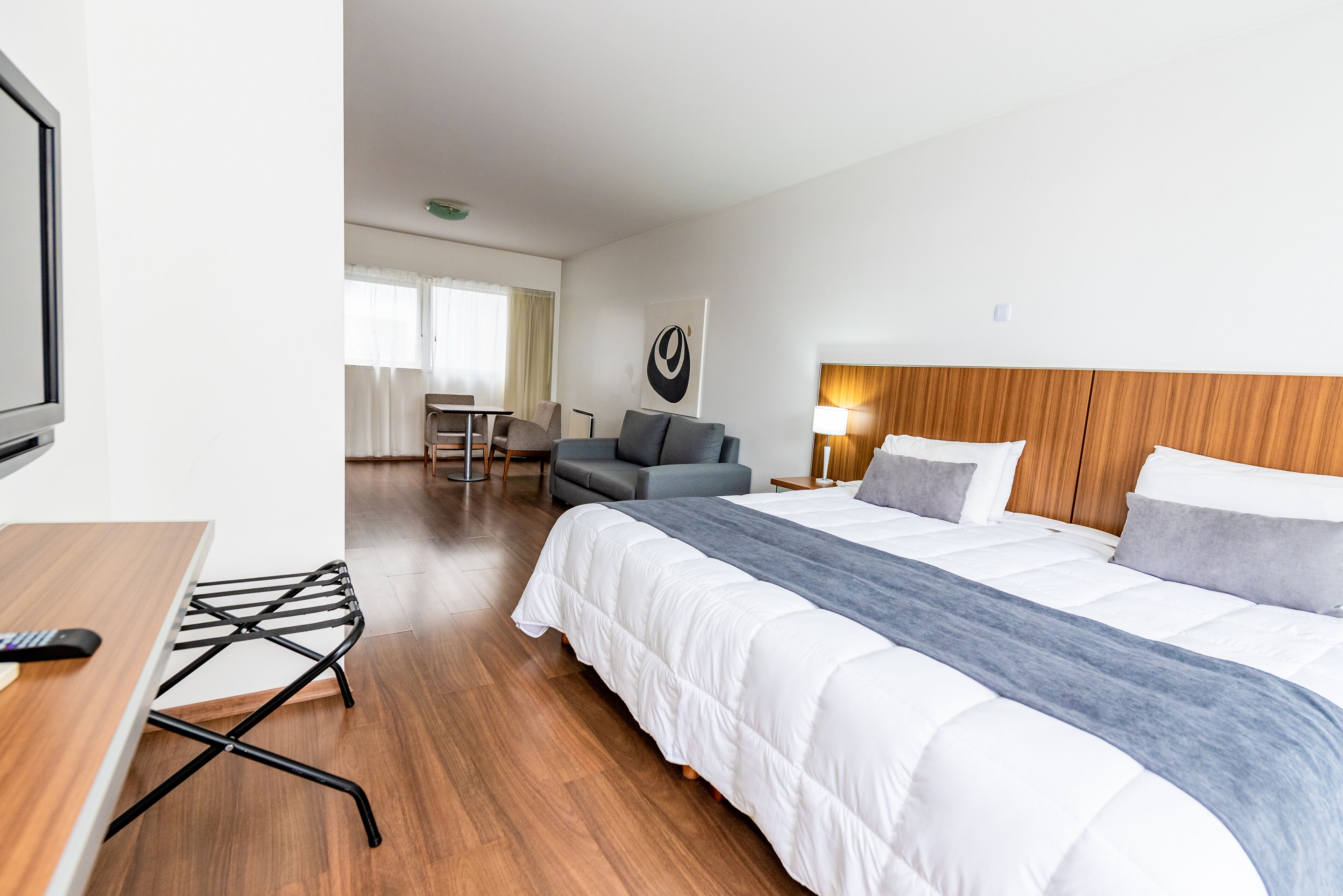 Una habitación de hotel con una cama grande, un escritorio, una silla y un televisor.