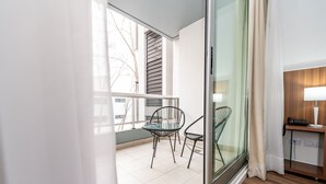 A modern room with a balcony, a dining table with chairs, a wooden floor, and a small desk with a lamp. - Hotel Bys Palermo (Buenos Aires)