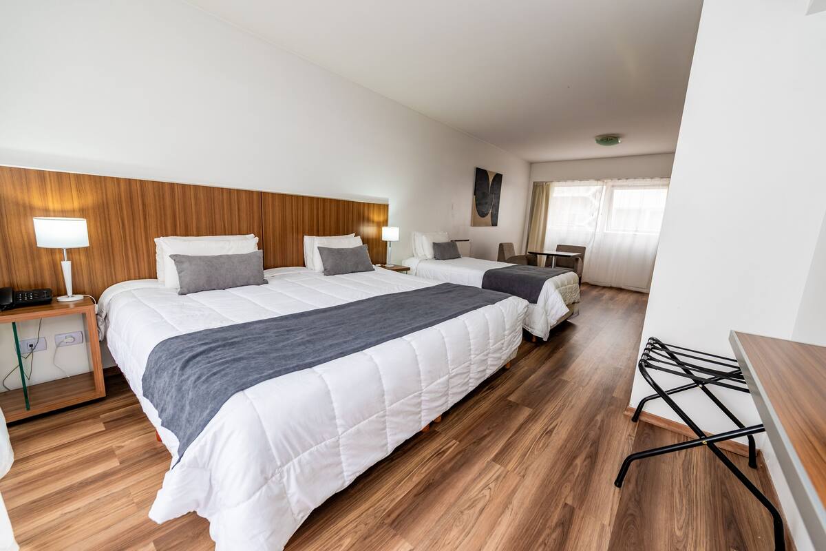 A hotel room with a large bed, bedside tables, a desk, and a chair.