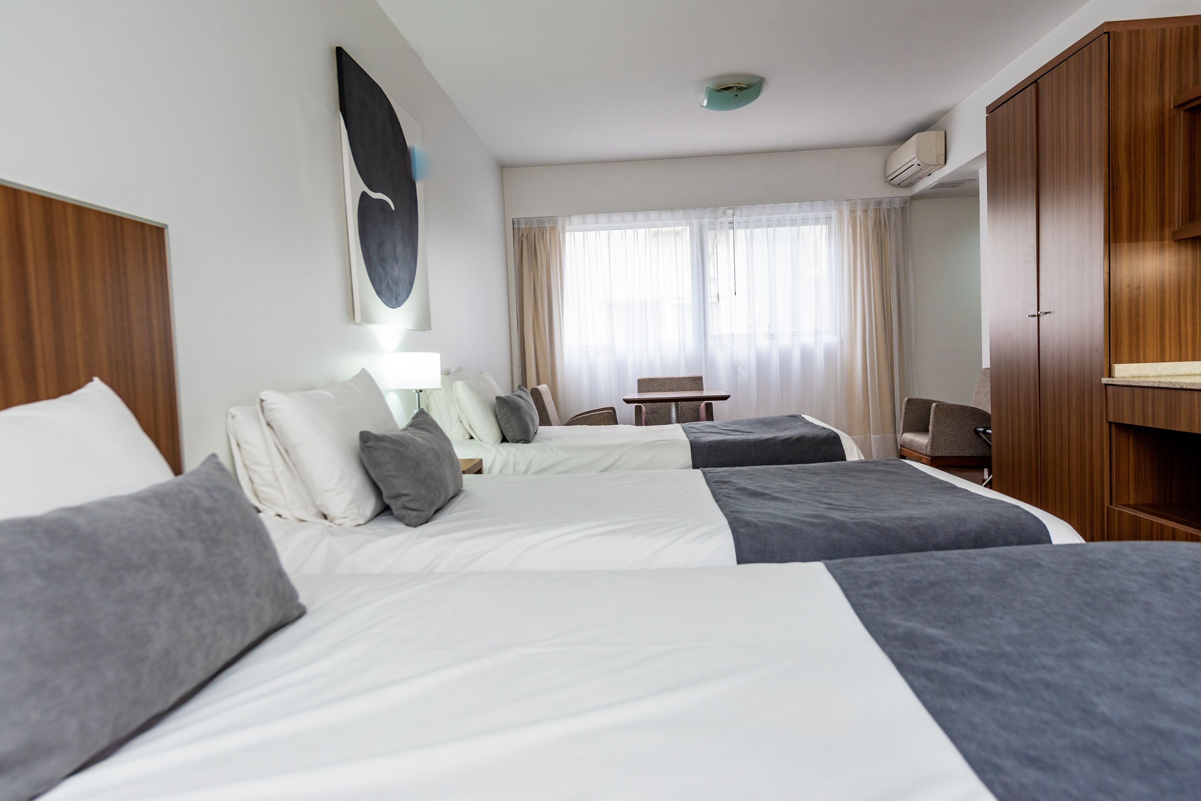 Habitación de hotel con dos camas, un escritorio, una silla y un armario.