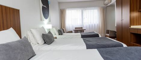 Habitación de hotel con dos camas, un escritorio, una silla y un armario.