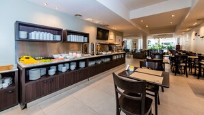 A modern restaurant with a long counter, multiple seating areas, and a variety of dishes displayed on the counter. - Hotel Bys Palermo (Buenos Aires)