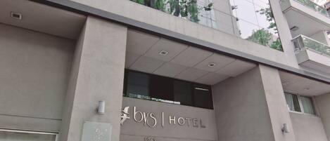 A hotel entrance with a glass facade, a sign reading "bys HOTEL", and a number "1263".