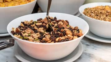 A bowl of mixed nuts and dried fruits on a white plate.
