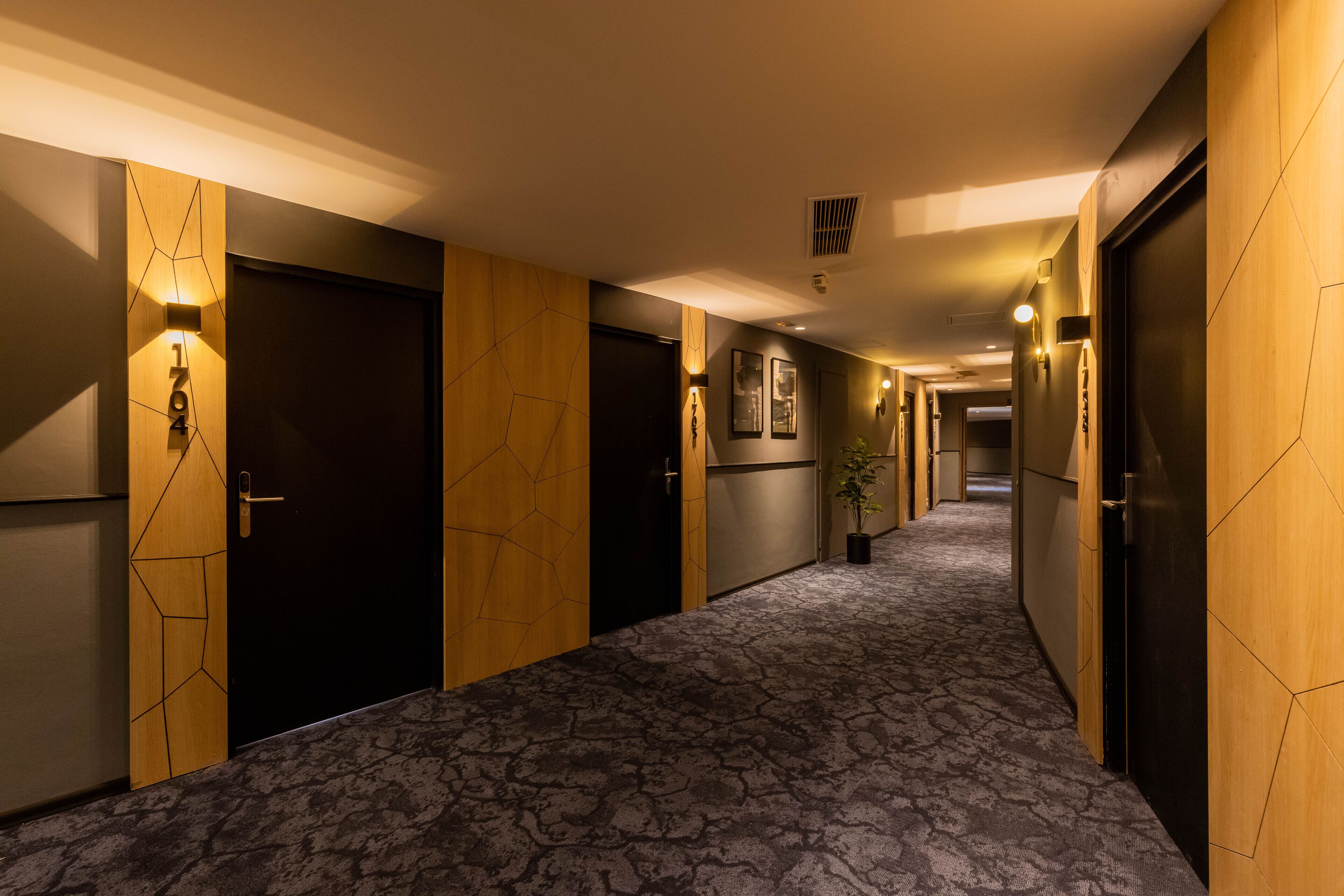 A hotel hallway with patterned carpet, wooden paneling, and doors with a geometric design.