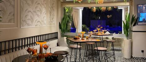 A modern lounge area with a round table, bar stools, and a sofa.