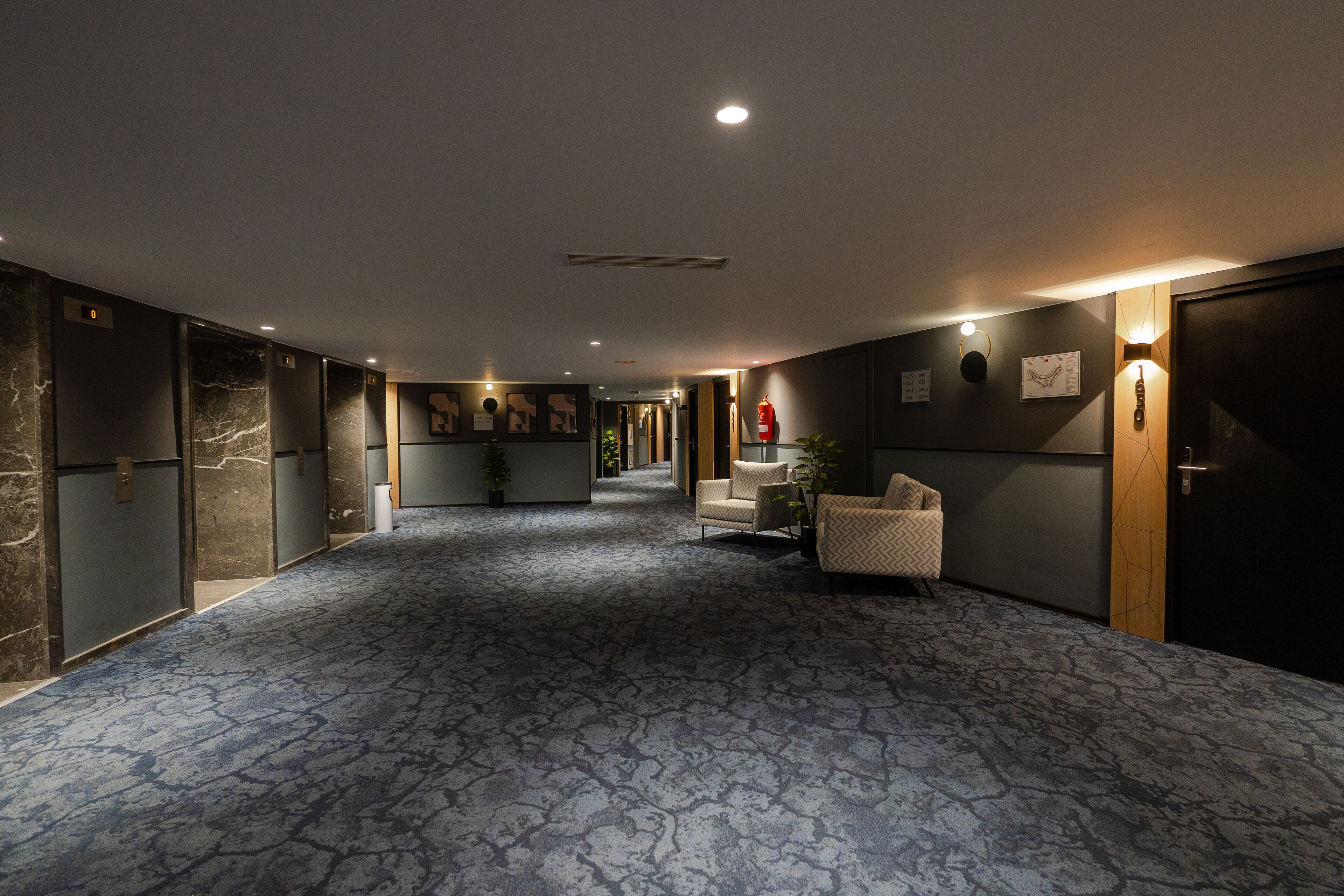 A hotel lobby with a patterned carpet, seating area, and a reception desk.