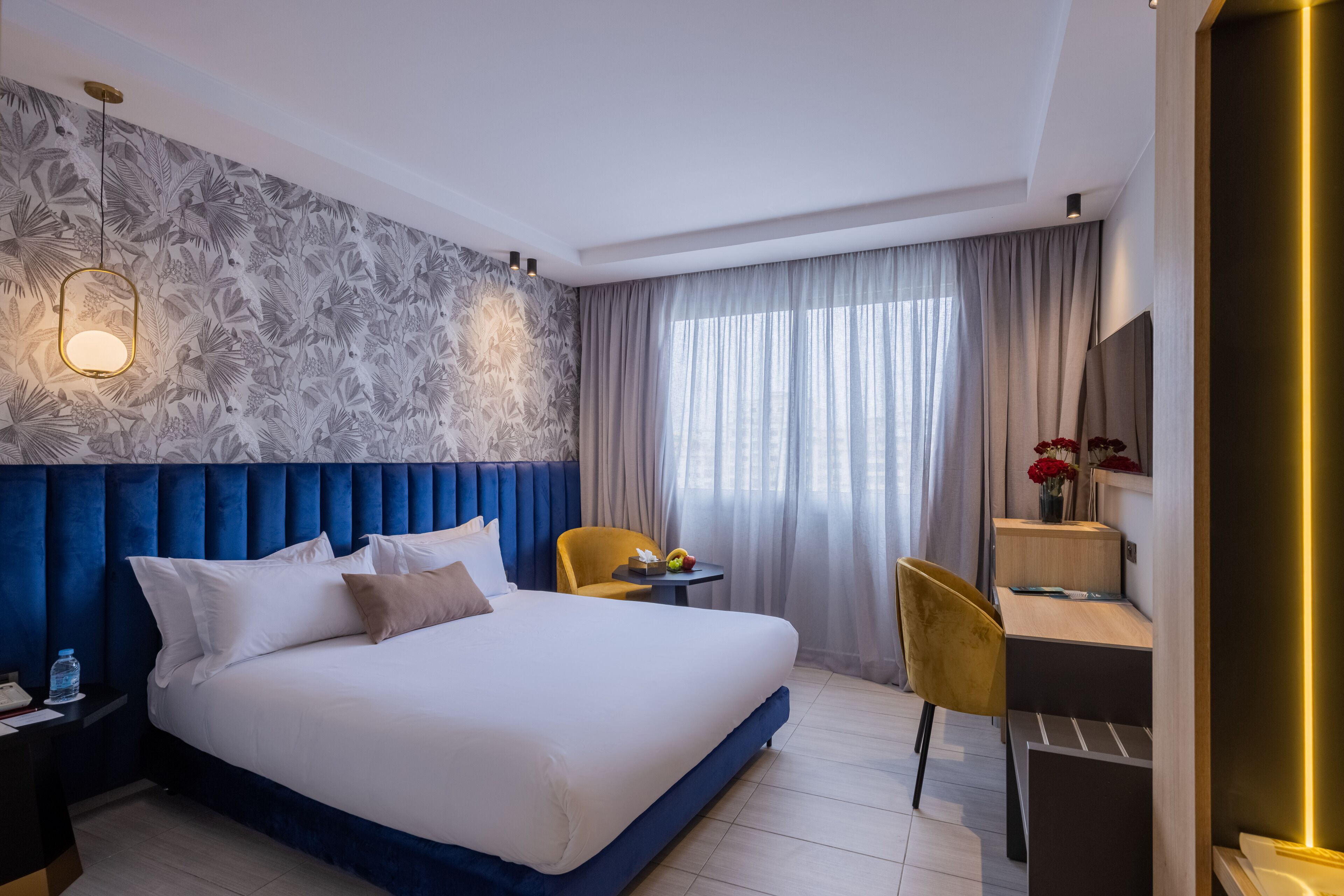 A modern hotel room with a large bed, a desk, and a chair.