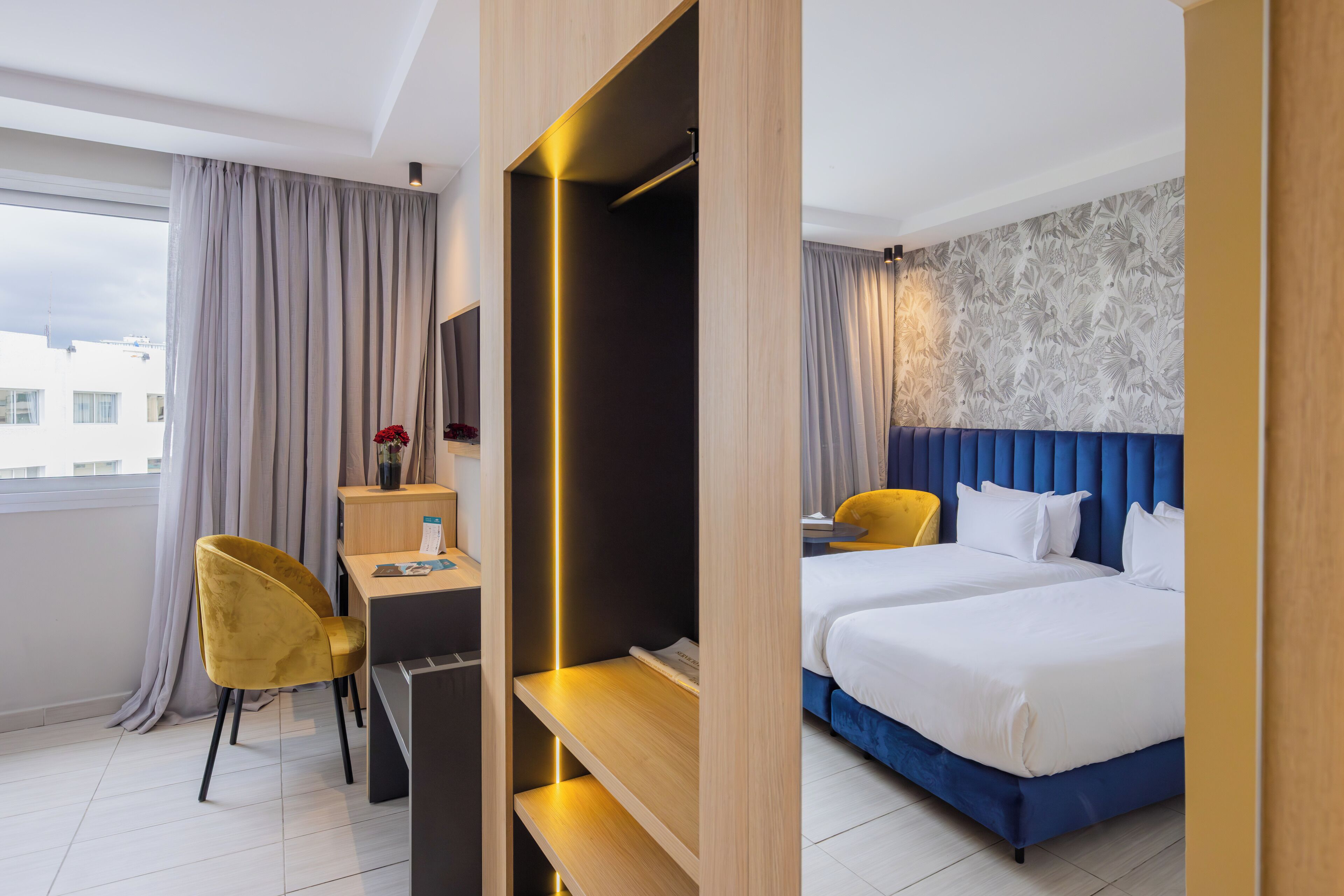 Habitación de hotel con cama, escritorio, silla y vista a la ciudad.