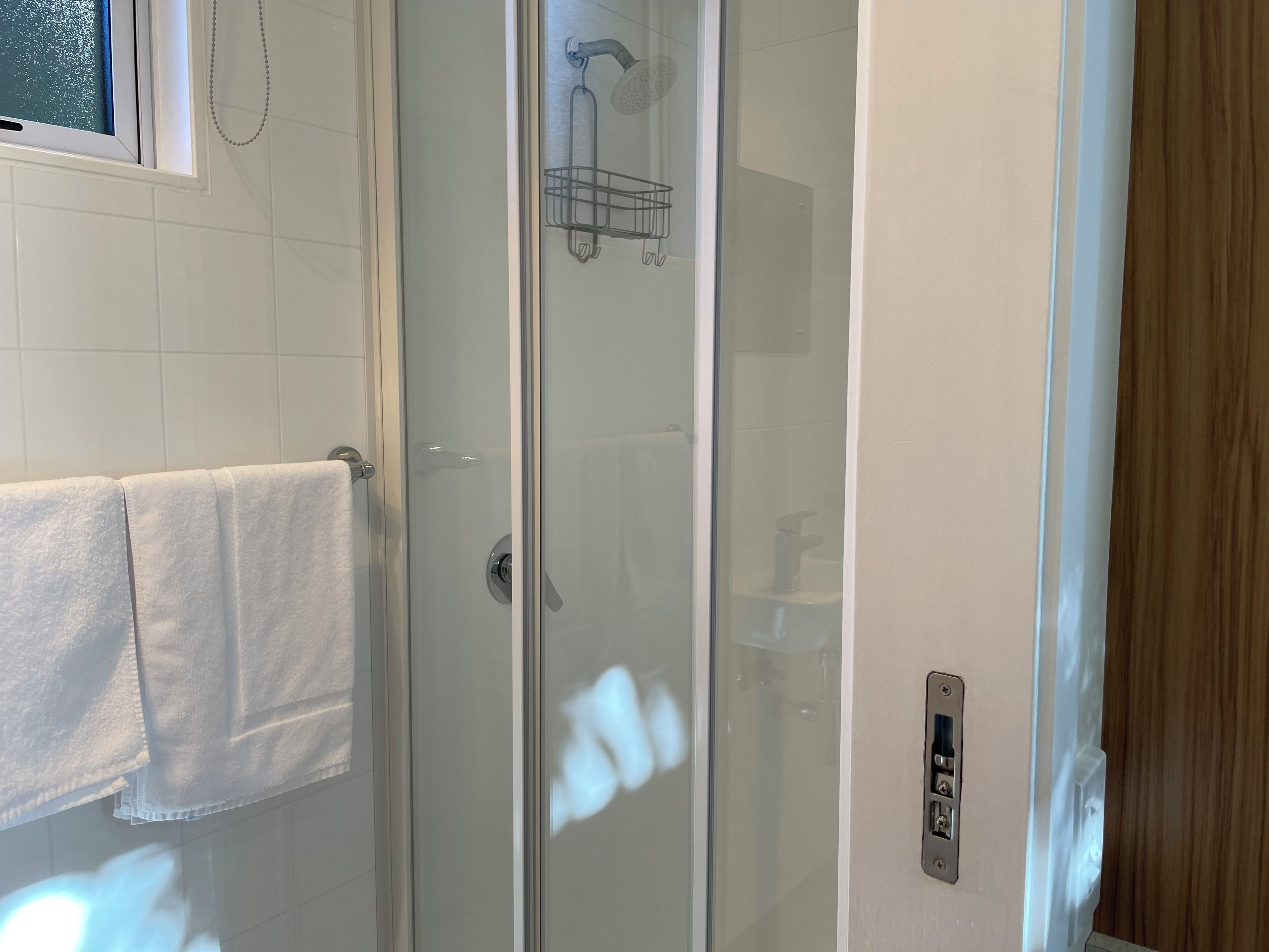 A glass-enclosed shower area with a towel rack and a control panel on the wall.