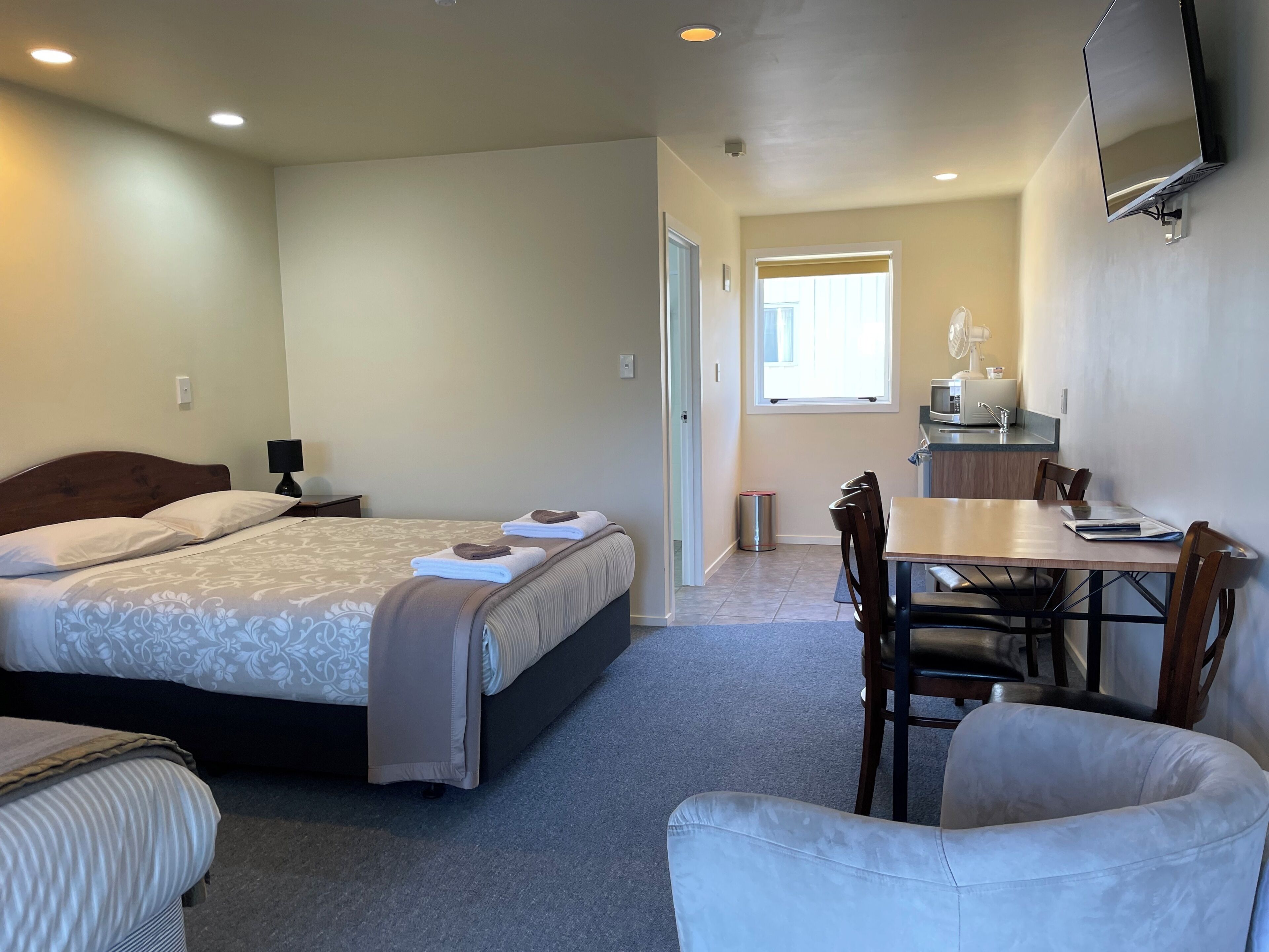 A hotel room with a bed, a desk, a chair, and a television.