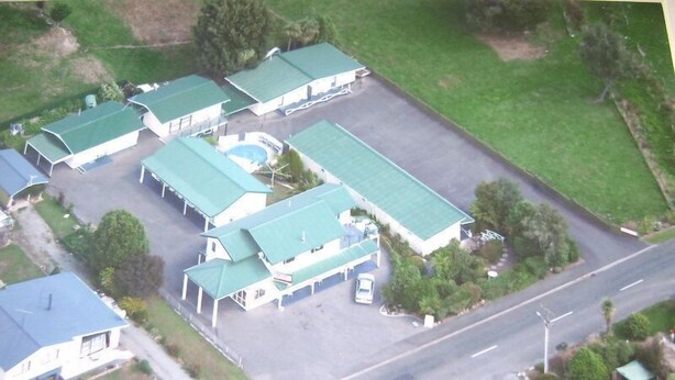 A multi-story building with a green roof, several parking spaces, and a swimming pool.