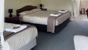 A hotel room with two beds, a large window, and a door leading to another room. - Mataki Motels (Murchison)