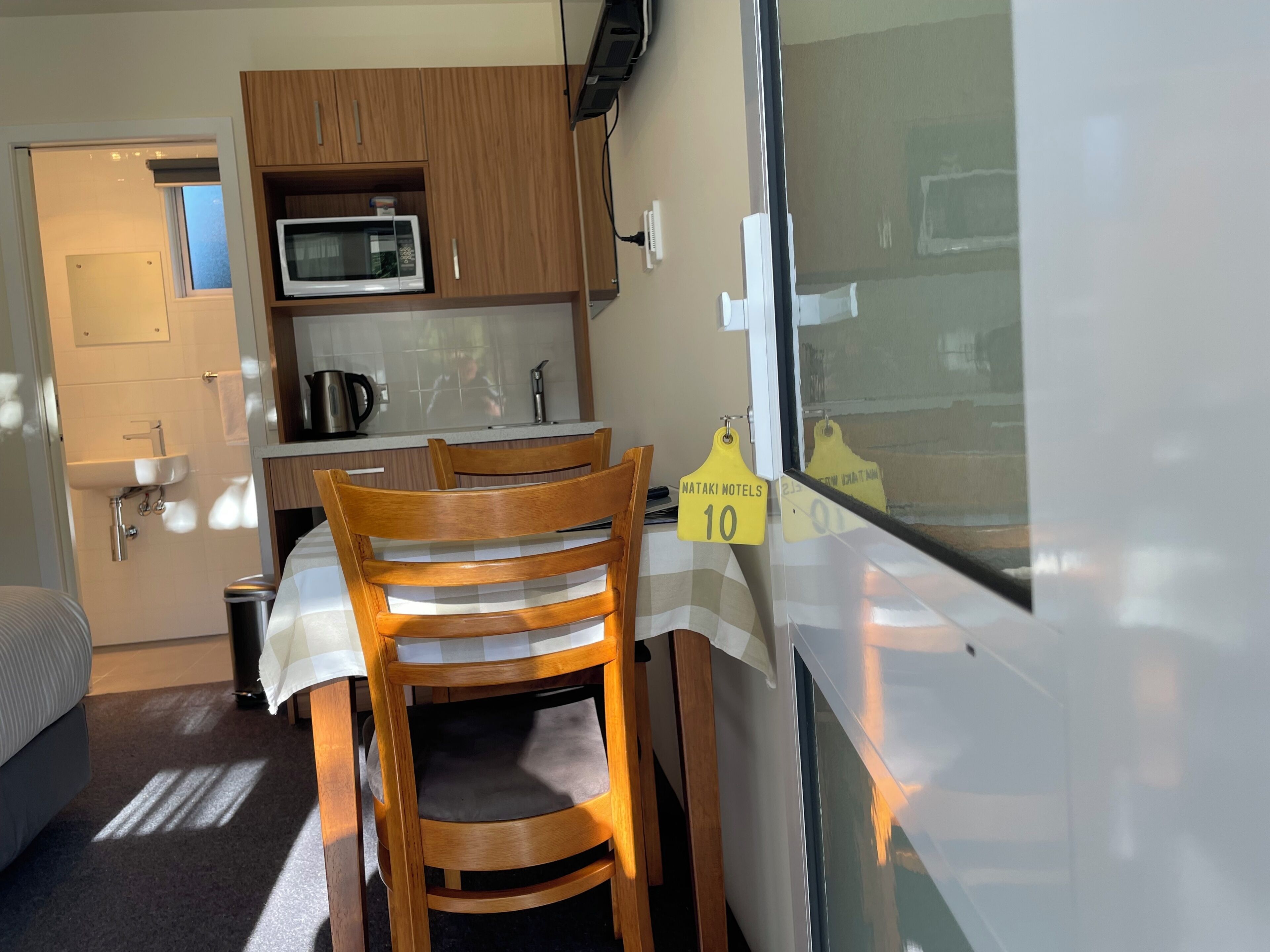 Una kitchenette compacta con microondas, pileta y muebles de madera.