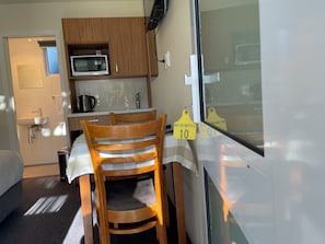Una kitchenette compacta con microondas, pileta y muebles de madera.