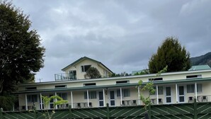 A two-story building with a green roof, multiple windows, and a balcony. - Mataki Motels (Murchison)