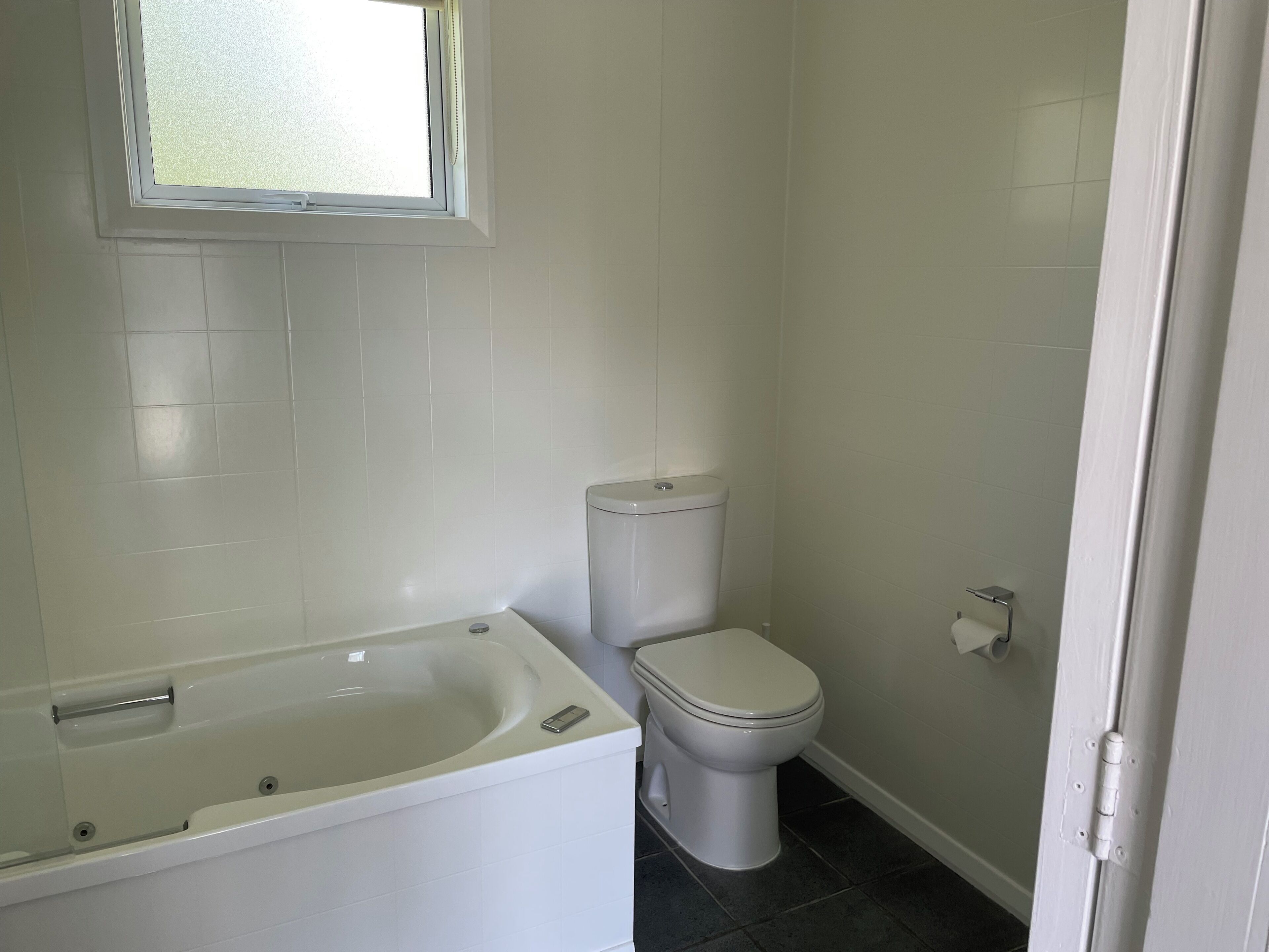 Un baño con bañera, inodoro y ventana.