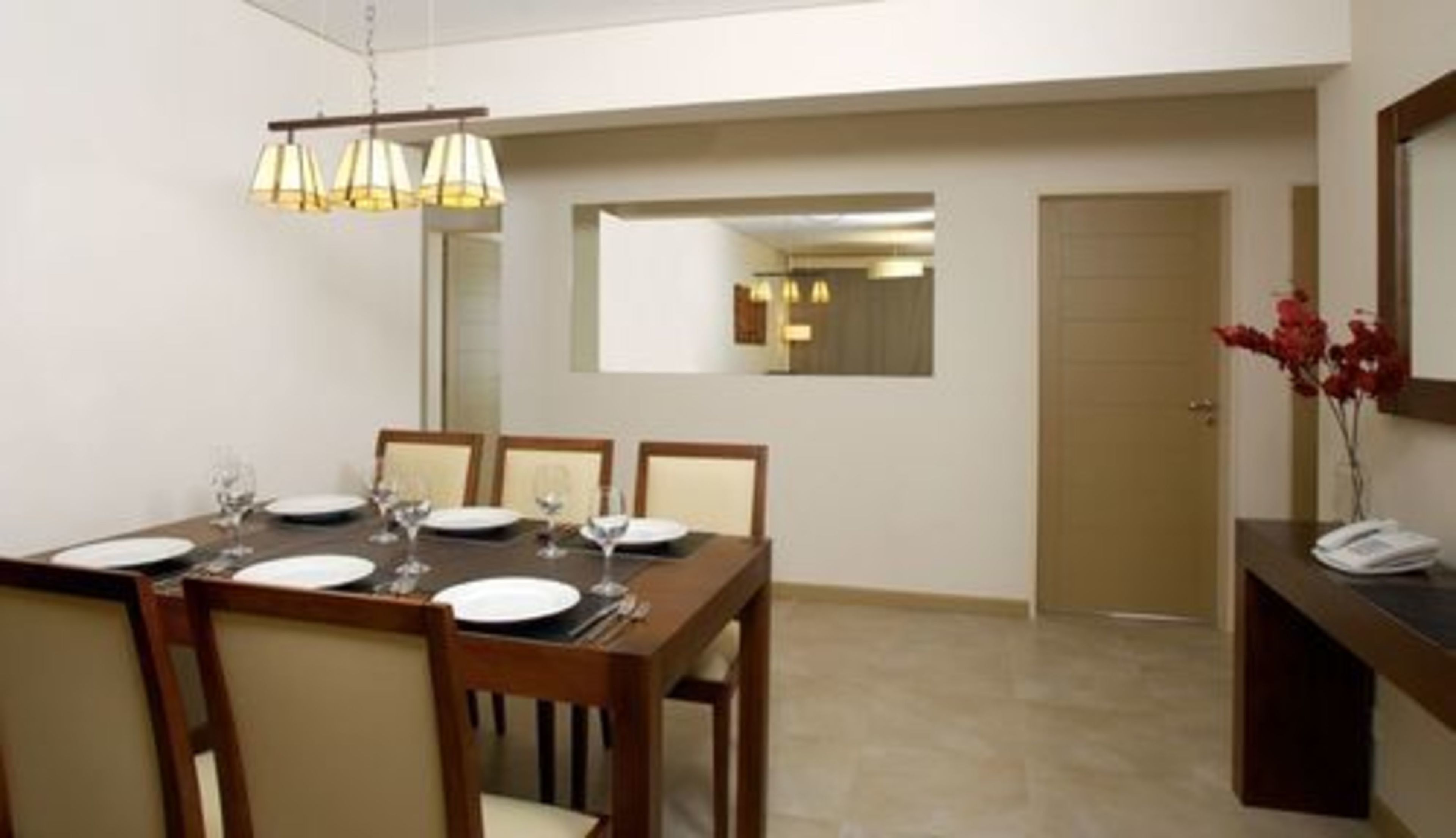 A dining area with a wooden table set for four, chairs, and a hanging light fixture.