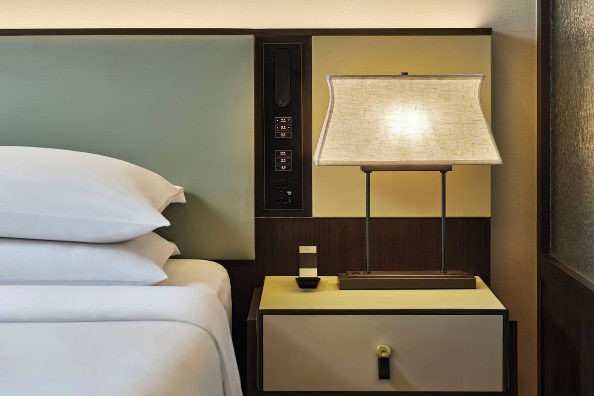 Une chambre d’hôtel avec un lit, une table de chevet avec une lampe et une œuvre d’art accrochée au mur.