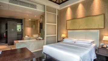 Een moderne hotelkamer met een groot bed, een aparte badkamer, een bureau en een groot kunstwerk aan de muur.