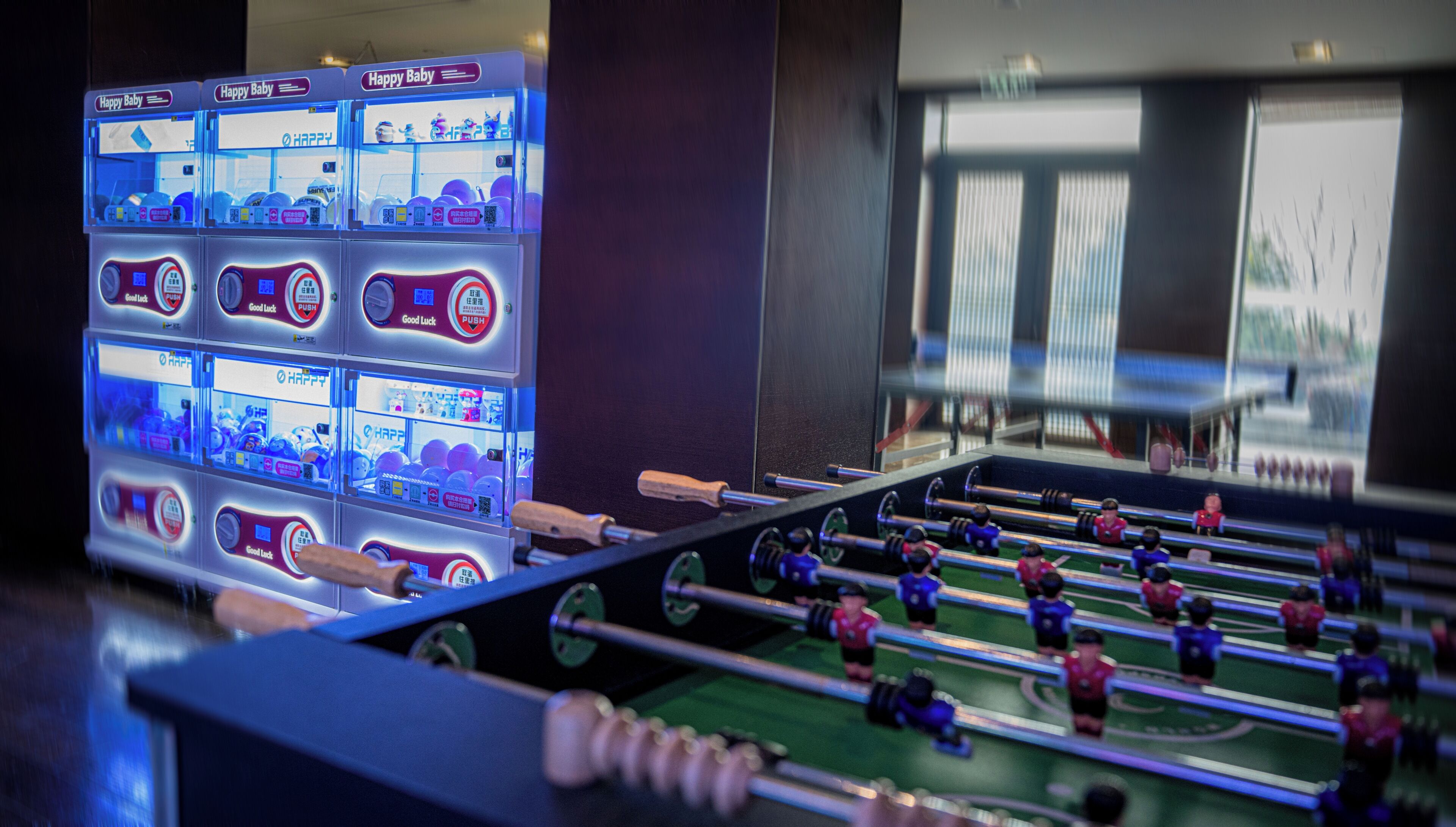 A foosball table with multiple players and a row of arcade games labeled "Happy Baby".