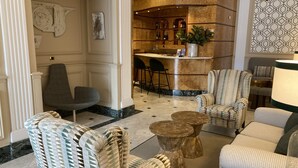 Un vestíbulo con zona de bar, espacios para sentarse y una pared decorativa.