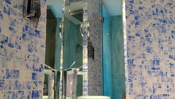 A bathroom with a white sink, a mirror, and blue mosaic tiles.