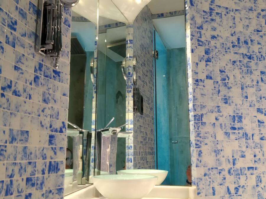 A bathroom with a white sink, a mirror, and blue mosaic tiles.