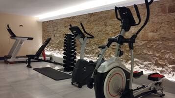 A gym with exercise equipment including a treadmill, elliptical, and stationary bike.