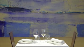 A table set for dining with a white tablecloth, two wine glasses, and folded napkins.