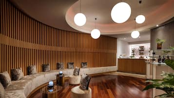 A modern lobby with a curved seating area, wooden panel walls, and a reception desk.