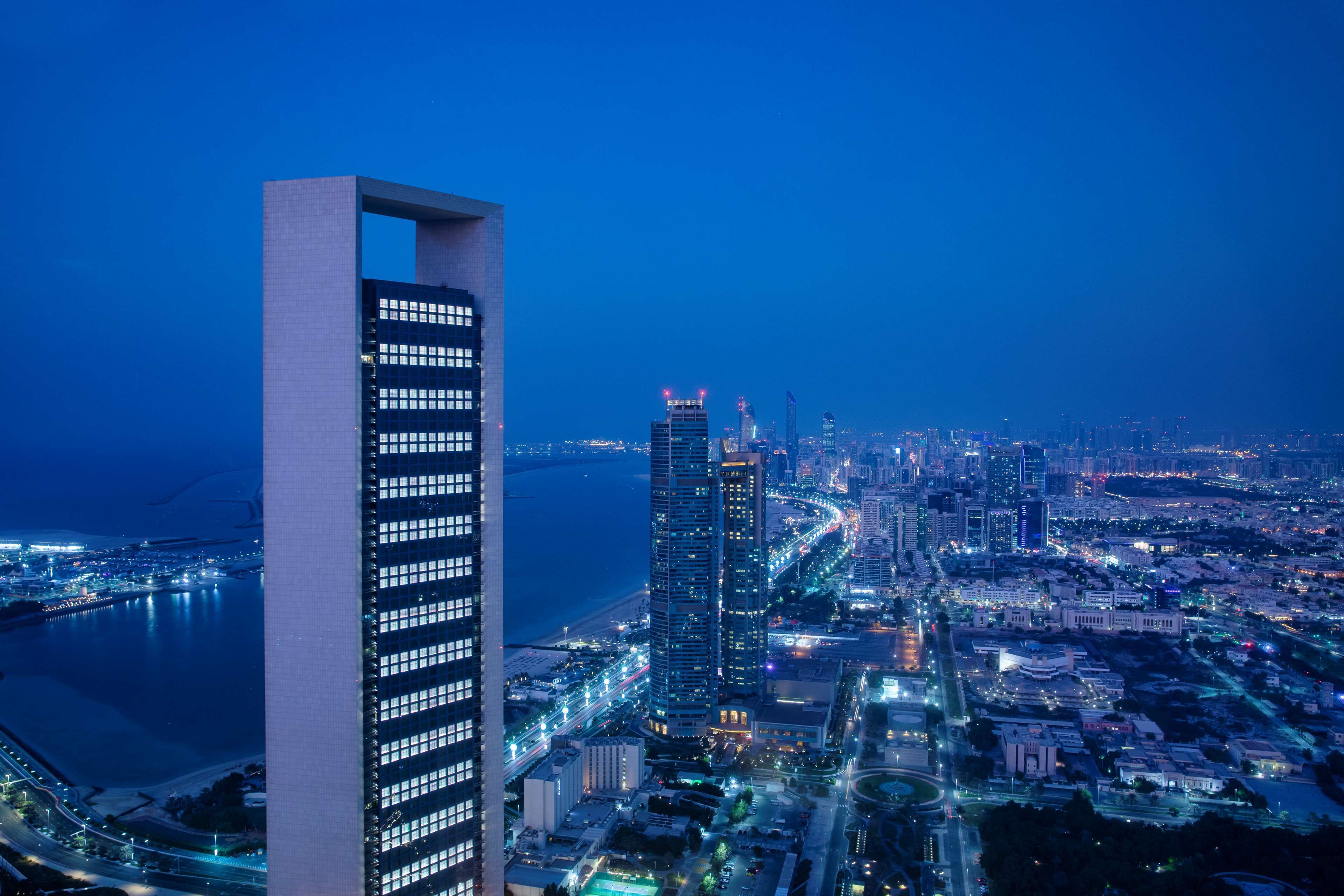 A high-rise building with a modern architectural design, surrounded by a cityscape with illuminated streets and buildings.
