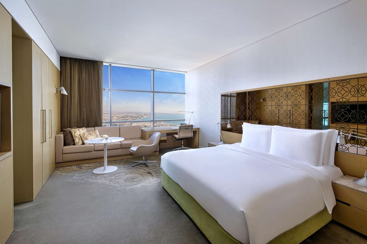 Habitación de hotel con una cama grande, un sofá, un escritorio y vistas a la ciudad.