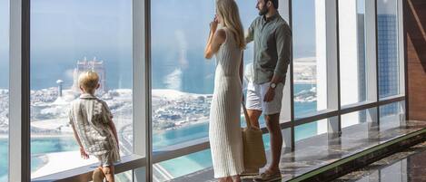A high-rise hotel with a panoramic view of a coastal cityscape, including a prominent tower and a beach.