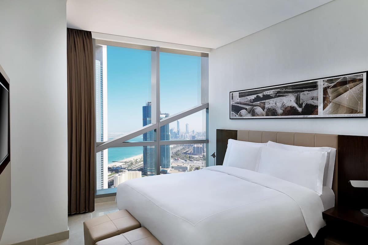 Habitación de hotel con una cama grande, vistas a la ciudad y un cuadro en la pared.