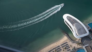 An aerial view of a modern hotel with a unique architecture, a pool, and a beach area.