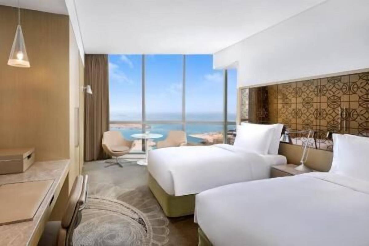 Habitación de hotel con cama, televisión, escritorio, silla y vista al océano.