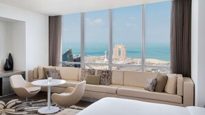 A modern hotel room with a large window offering a city view, a sofa, a small round table, and a bed. - Conrad Abu Dhabi Etihad Towers (Abu Dhabi)